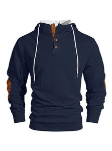 Détail du sweat à capuche bleu marine avec patte boutonnée et coudières à texture tricot