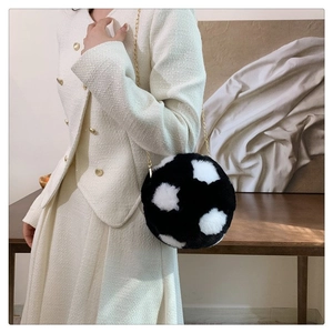 Detail of round plush crossbody bag with black white cow print and gold chain strap