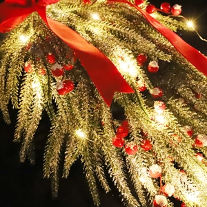 Artificial Christmas garland with red berries, pine needles, and warm LED lights