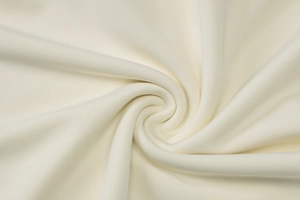 Macro shot of cream-white knit fabric texture showing soft stretch and spiral drape detail