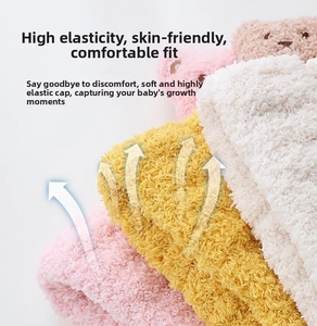 Close-up of soft plush knit baby beanies in pink yellow and cream with elastic texture