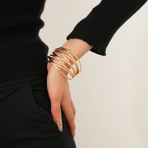 Detailed close-up of a layered gold-plated wrap bracelet on a model wearing black clothing