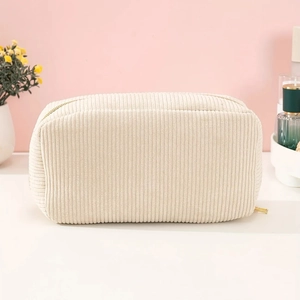 Close-up of beige corduroy cosmetic bag featuring vertical texture and golden zipper
