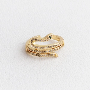 Macro shot of gold snake-shaped open ring featuring white and green cubic zirconia inlay