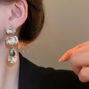 Detail shot of three-tier silver tassel earrings with square and teardrop crystals