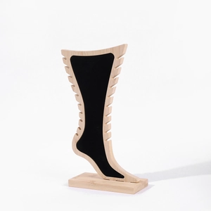 Detailed close-up of a wood and black velvet foot-shaped display stand for jewelry