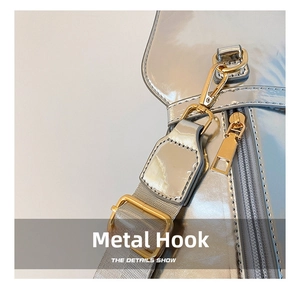 Detail of silver patent leather bag featuring premium gold hardware and grey textile strap