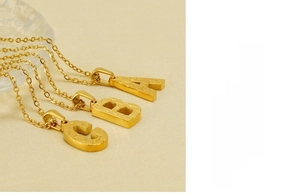 Detailed macro view of 18K gold plated stainless steel letter pendants with tiger texture
