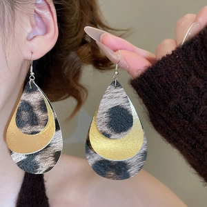 Close-up of leopard print leather teardrop earrings on a model wearing a brown sweater