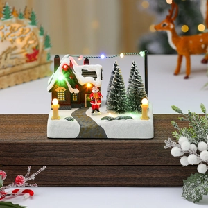 Detailed view of glowing resin Christmas music box with snowy miniature house and Santa
