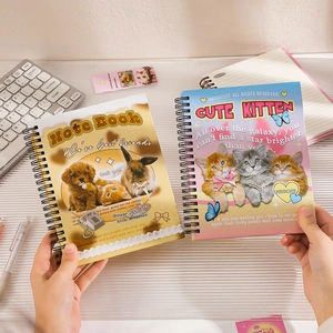 Close-up of cute cartoon cat and puppy spiral notebooks held by hand in a study setting