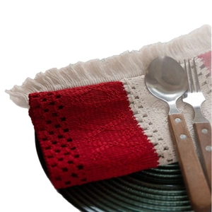 Festive red and beige striped cotton woven placemat with tassels on a dark tray