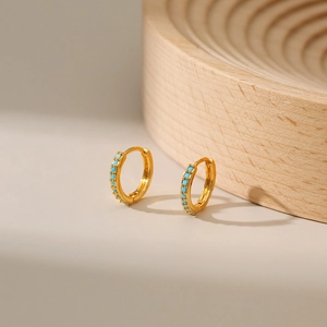 Macro view of 18K gold plated hoop earrings featuring inlaid turquoise gemstones