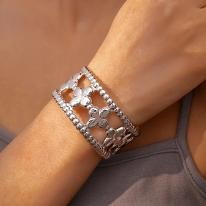 Close-up of a silver hollow clover bracelet with beaded edges on a female wrist
