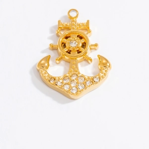 Détail macro du pendentif ancre et gouvernail doré orné de strass étincelants