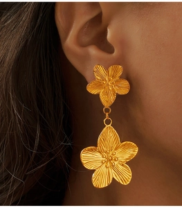 Gros plan de boucles d'oreilles fleurs dorées avec pétales texturés sur un mannequin