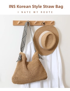 Detail of hand-woven straw shoulder bag with black and white striped fabric strap