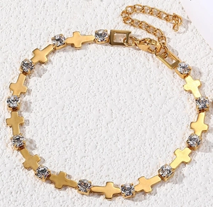 Detail of adjustable gold-tone cross bracelet with inlaid sparkling zircon stones