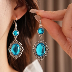 Detail of vintage bohemian silver hollow earrings with blue oval resin stones on model