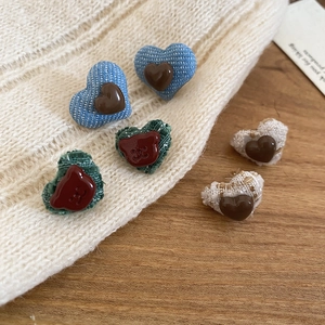 Close-up of heart and bear fabric earrings in denim and corduroy on a soft knit fabric