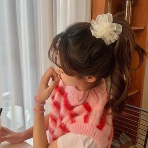 Close-up of a white camellia hair clip made of sheer mesh fabric on a high ponytail