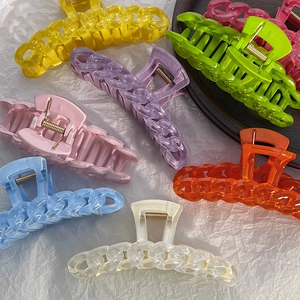 Macro detail of large candy-colored hair claws with a unique woven chain link design