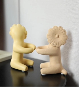 Close-up of modern ceramic lion figurines with floral heads in yellow and beige matte finish