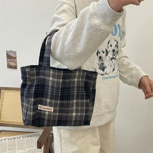 Close-up of the vintage plaid pattern and white fabric label on the large tote bag