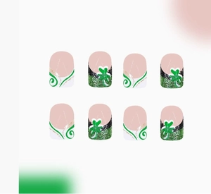 Détail de faux ongles Saint-Patrick avec motifs trèfles et paillettes vert brillant