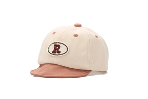 Détail d'une casquette bébé à visière souple avec broderie lettre R rouge en tissu coton