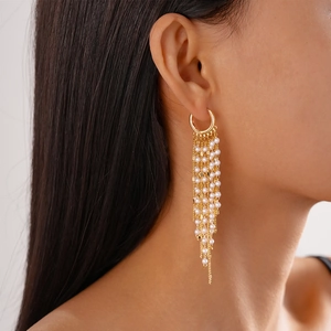 Boucles d'oreilles longues en perles avec placage or 18k portées de profil par un mannequin