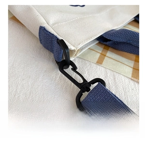 Detail eines schwarzen Kunststoffhakens und dunkelblauen Tragegurts an der Canvas Tasche