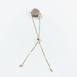 Detail of adjustable gold box chain bracelet with raw pink natural crystal stone