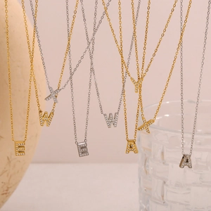 Dettaglio di ciondoli con lettere in oro 18K e argento con cristalli su catene fini
