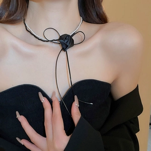 Detail of elegant black fabric rose and ribbon bow on a double-layer pearl necklace