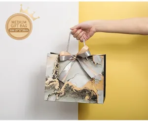 Medium marble gift bag with gold leaf and satin bows, size 25x12x20cm, shown in use
