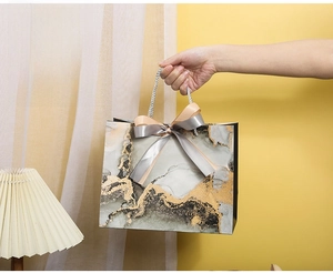 Medium marble gift bag with gold leaf and satin bows, size 25x12x20cm, shown in use