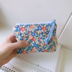 Close-up of floral cotton pouch with blue zipper and simple wish woven label