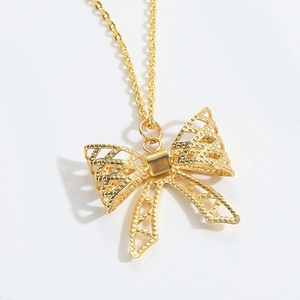 Detail of a gold hollow bow pendant necklace with intricate geometric pointelle patterns