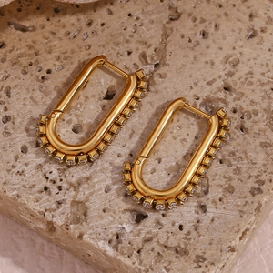 Detailed macro of a 18k gold plated U-shaped hoop earring with zircon inlay on stone