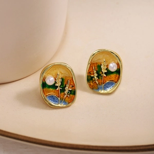 French vintage enamel earrings with white pearl detail on beige ceramic plate