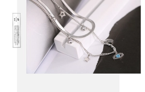 Detail of silver double-layered snake chain with evil eye and star charms