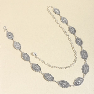 Close-up of vintage silver metal chain belt with bohemian oval carved charms and lobster clasp