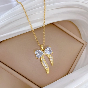 Close-up of golden bow pendant with sparkling heart-shaped crystals on an elegant necklace