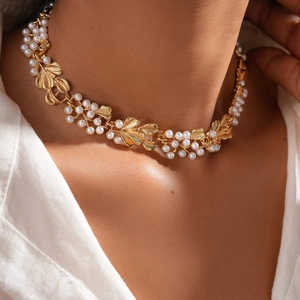 Detail of vintage gold necklace with pearl accents and leaf motifs on a female model