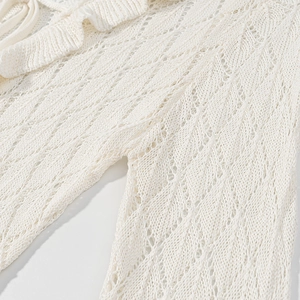 Close-up of white lace dress showing delicate hollow knit texture and fabric details