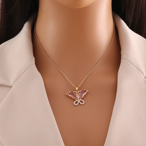 Close-up of gold butterfly pendant with pink crystals and clear zircons on a neck