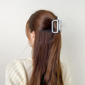 Vue arrière d'une pince à cheveux carrée noire et blanche sur cheveux longs bruns