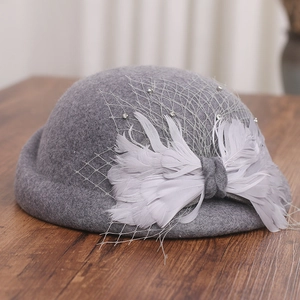 Detail of grey wool fascinator hat featuring delicate feathers and elegant mesh veil