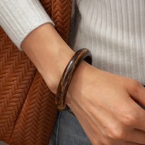 Detail of amber acrylic geometric bangle showing marble texture and polished finish